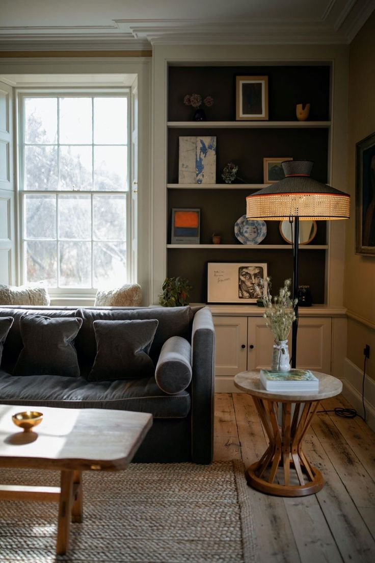 a living room filled with furniture and a lamp on top of a coffee table in front of a window