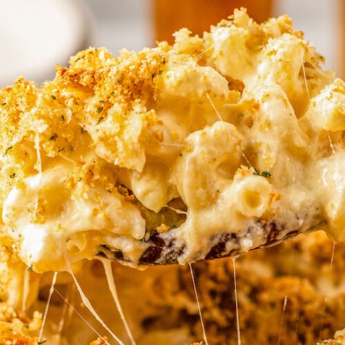 a spoon full of macaroni and cheese being lifted from a casserole dish