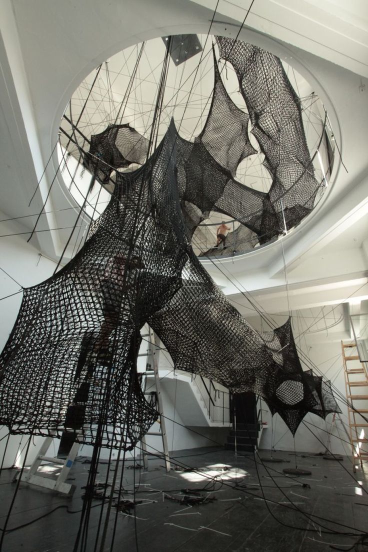 an art installation in the middle of a room with multiple pieces of wire hanging from the ceiling