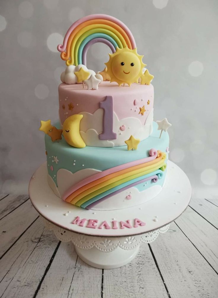 a birthday cake decorated with rainbows, stars and the number one on it's side