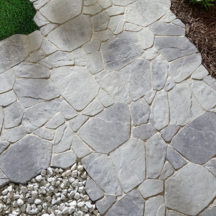 a stone walkway with gravel and grass in the background