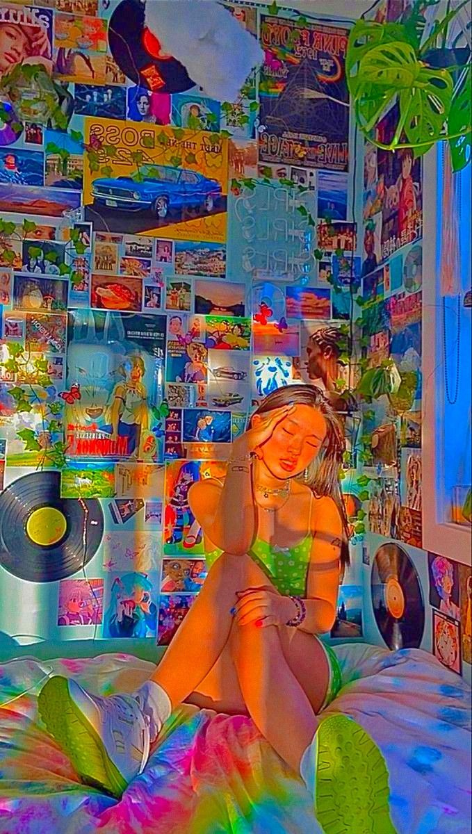 a woman sitting on top of a bed next to a wall covered in posters and cds