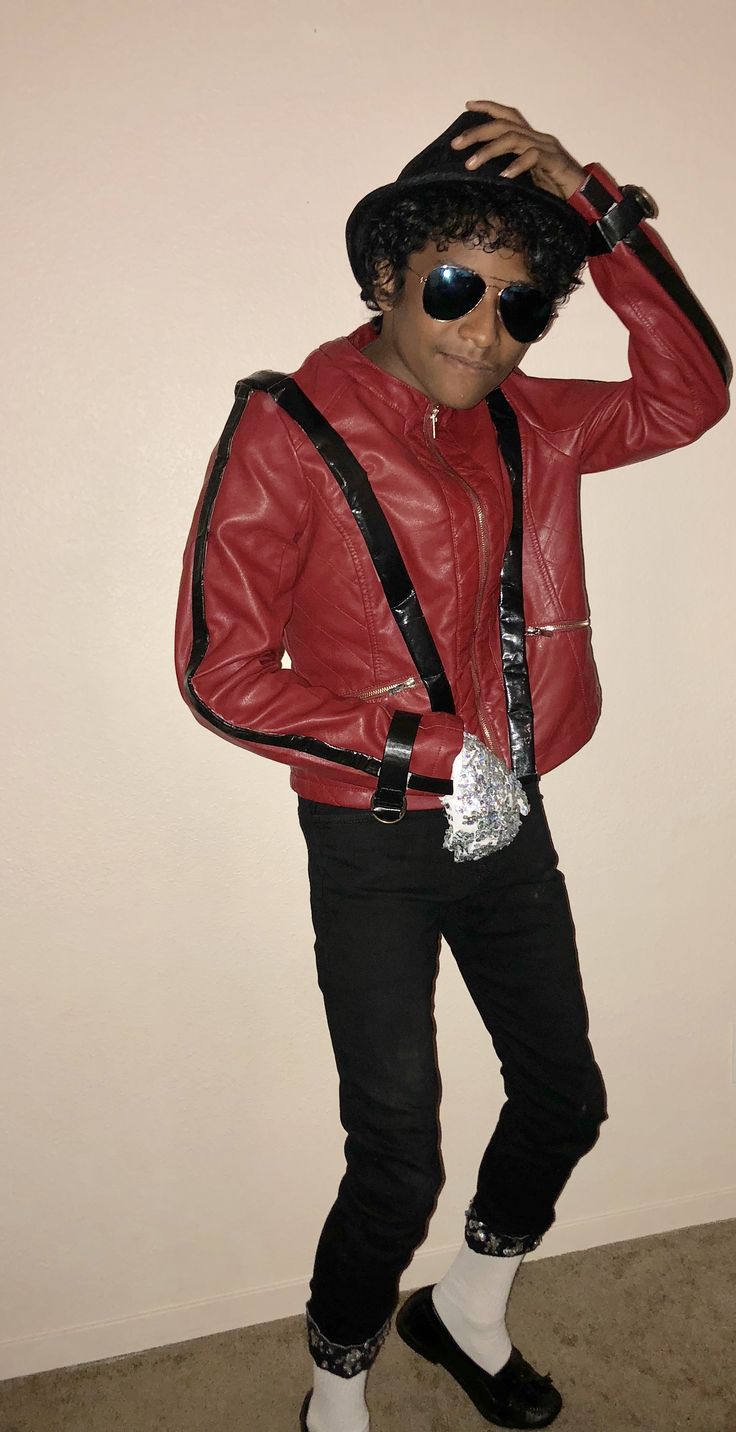 a man in a red leather jacket and black pants is holding his hands on his head