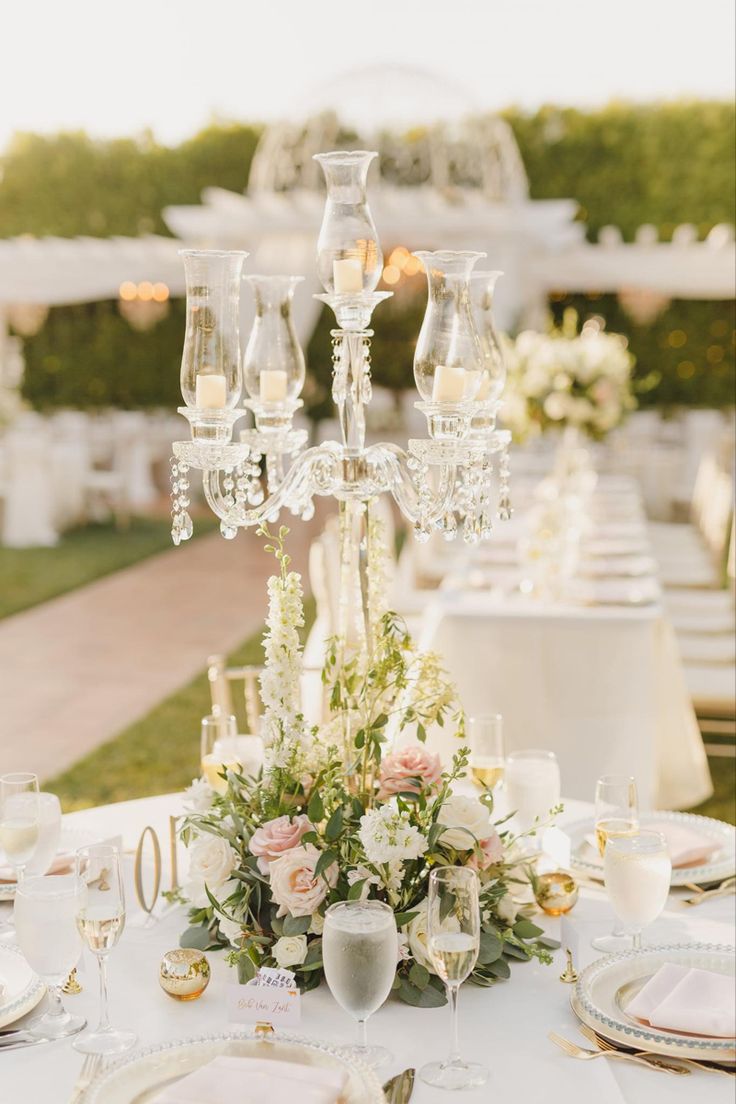 the table is set with champagne glasses, flowers and candles for an elegant wedding reception