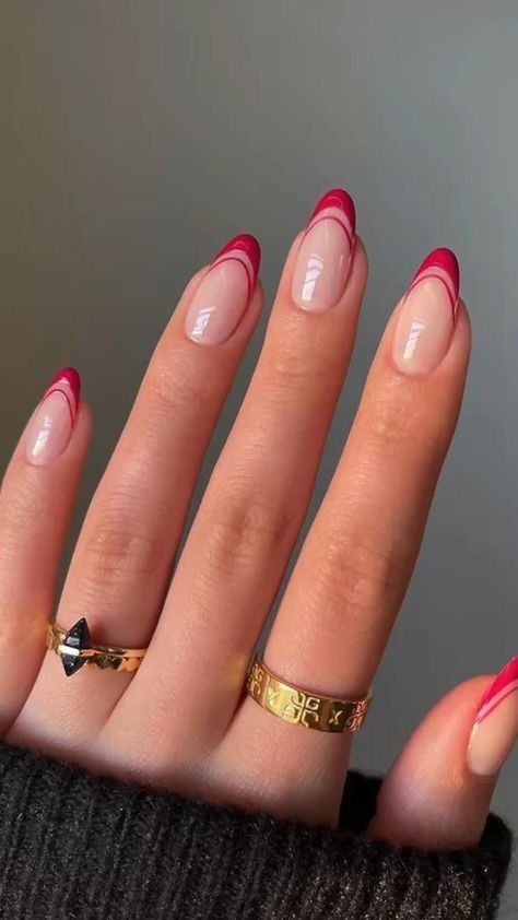 a woman's hand with red and gold manicures on it, holding onto her nails