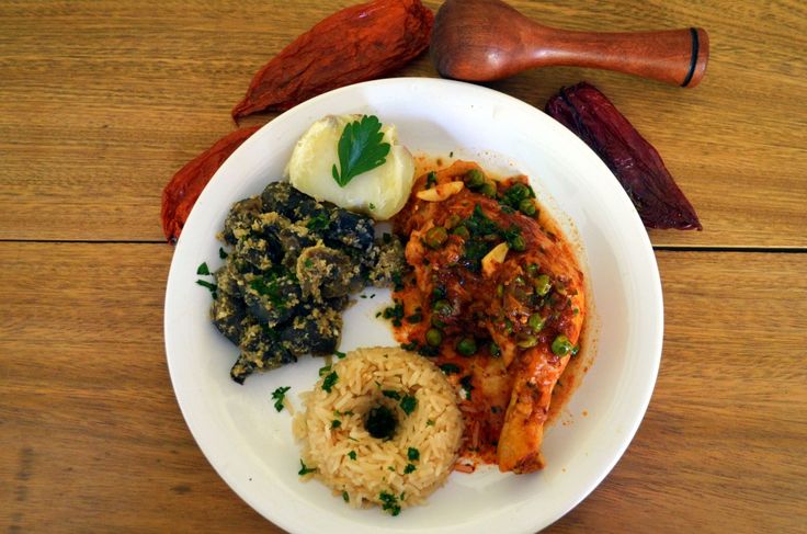 a white plate topped with meat, rice and veggies on top of a wooden table