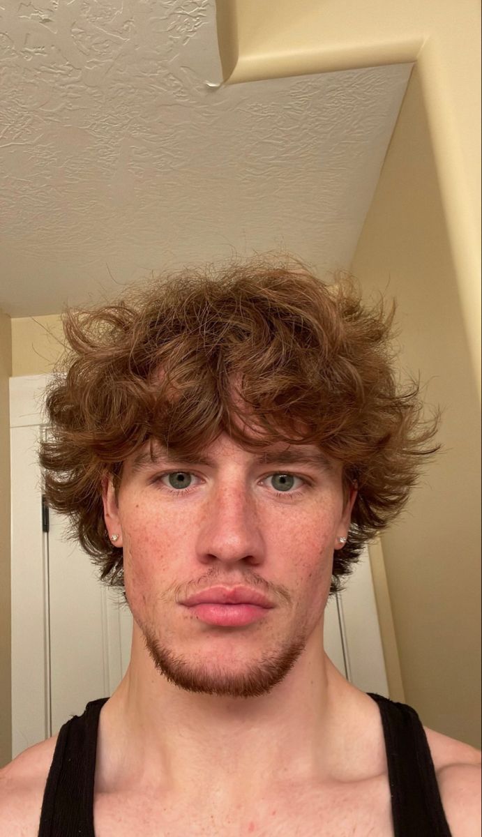 a man is taking a selfie in the mirror with his hair blowing back and blue eyes