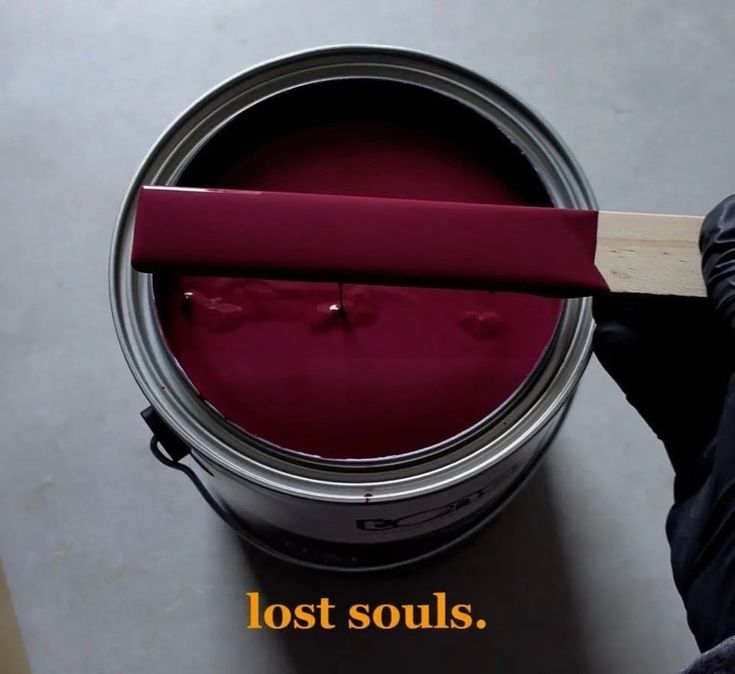 a person holding a red paint can with the words lost souls on it