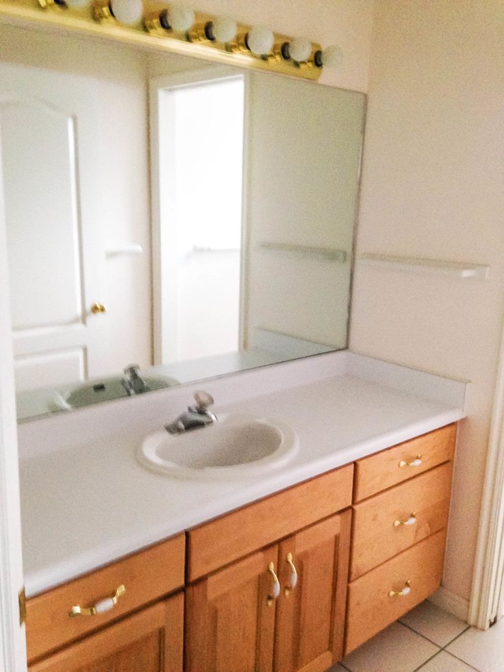 a bathroom with a sink, mirror and tiled floor in it's center area