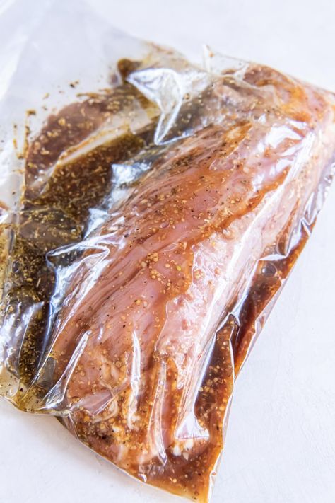 a piece of meat wrapped in plastic sitting on top of a white tableclothed surface