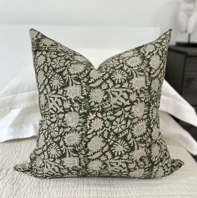 a black and white pillow sitting on top of a bed next to a night stand