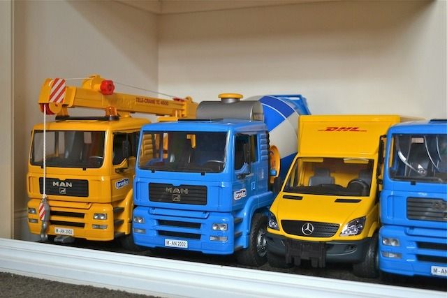 several toy trucks are lined up on a shelf