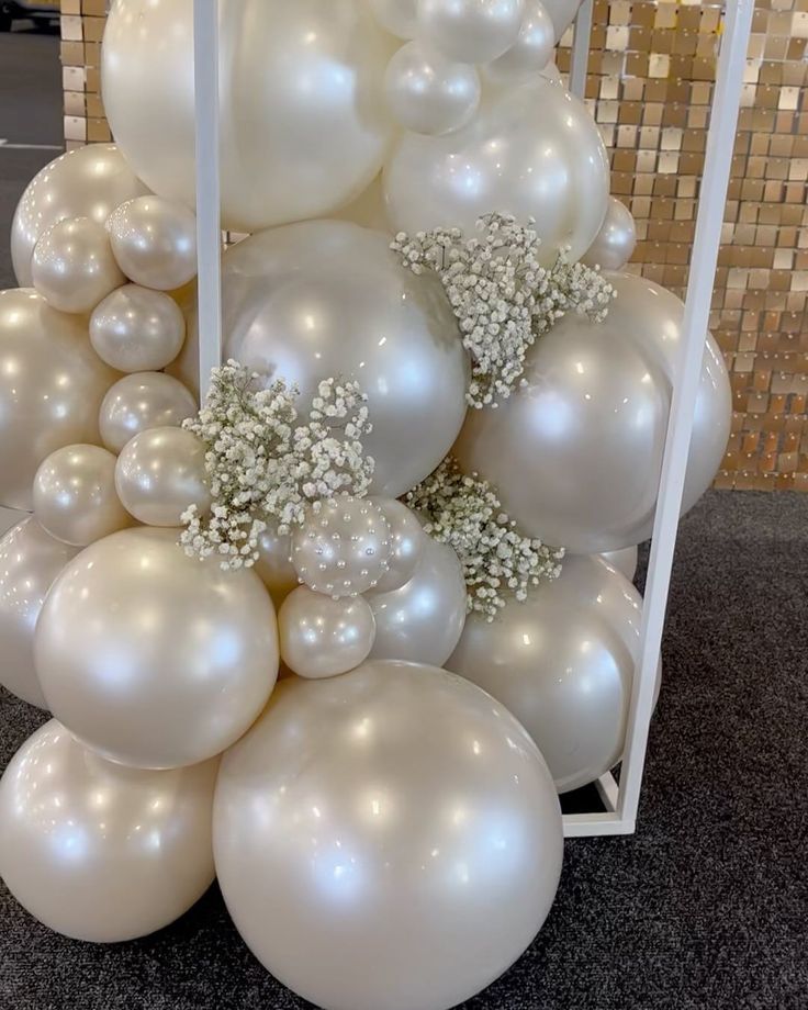 white balloons are stacked on top of each other in the shape of a christmas tree