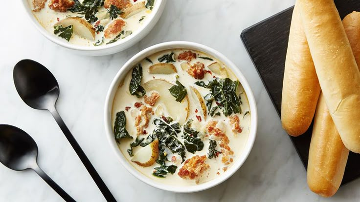 two bowls of soup with bread on the side