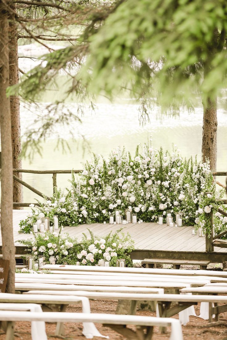 an outdoor ceremony setup with white flowers and greenery