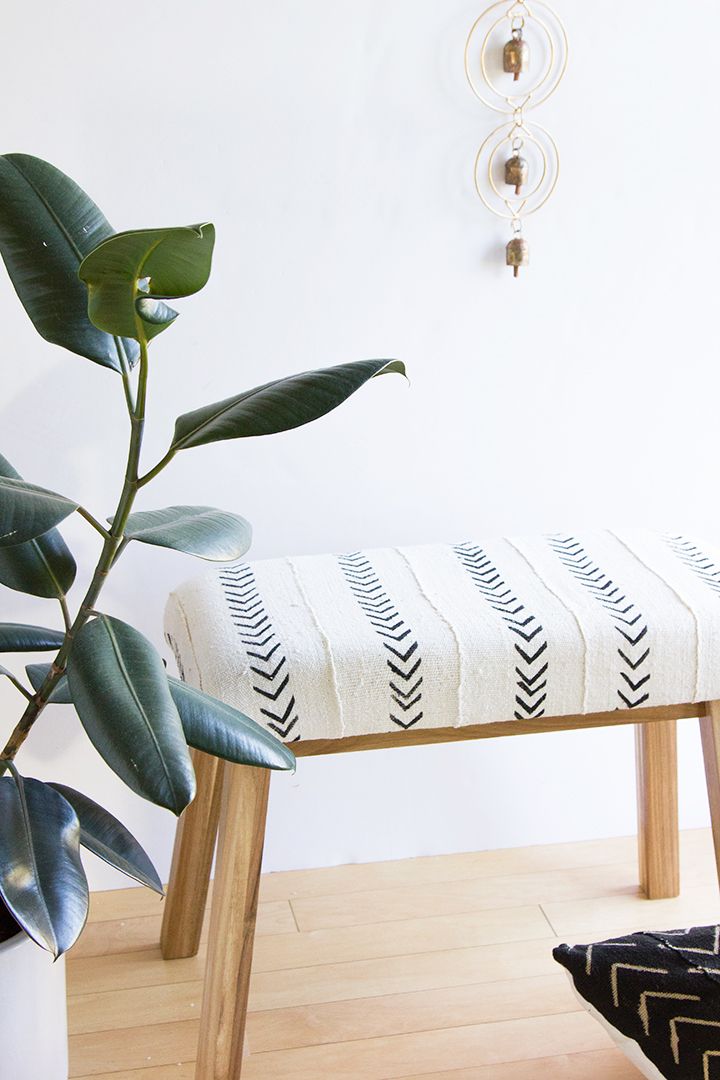 a white bench sitting next to a green plant in a room with wood flooring