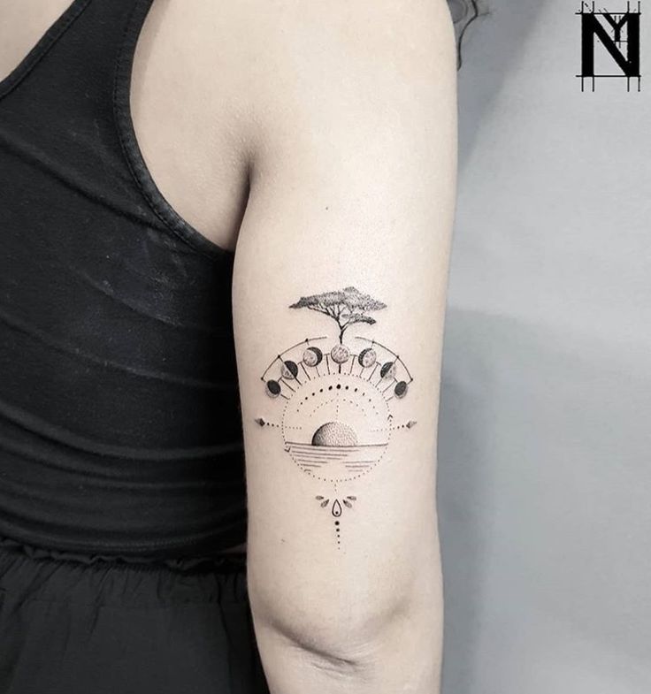 a woman with a tattoo on her arm that has an image of the sun and moon