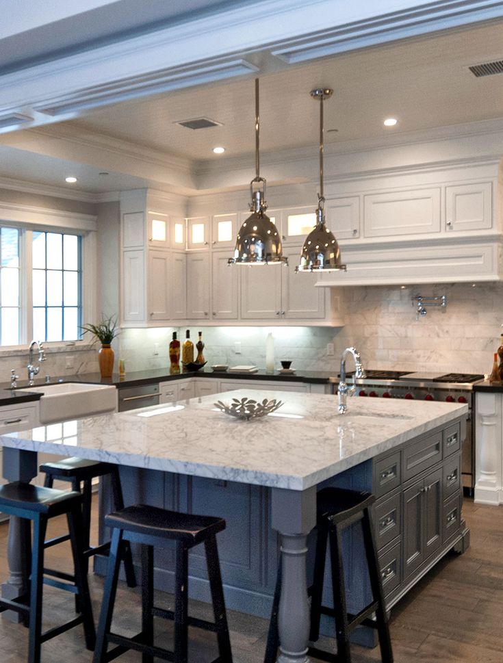 a large kitchen with an island in the middle and three stools at the end