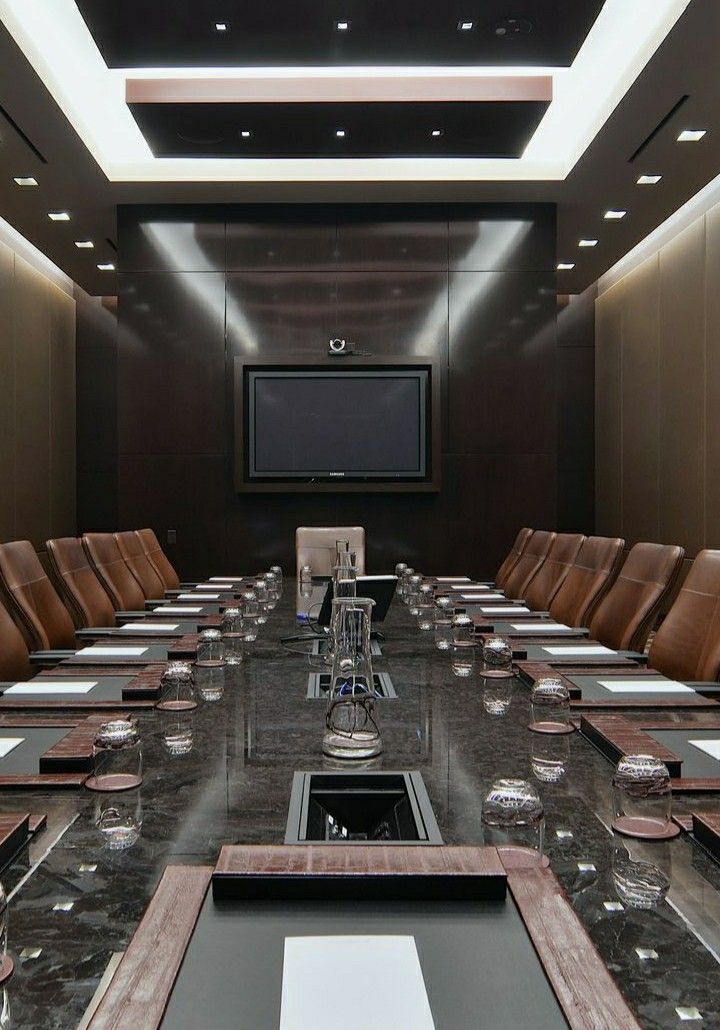 a large conference room set up for a meeting with brown leather chairs and a flat screen tv