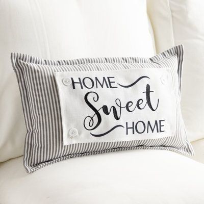 a pillow that says home sweet home sitting on a white couch with black and white pillows