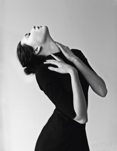 a woman in a black dress is posing with her hands on her chest and wearing yellow bracelets