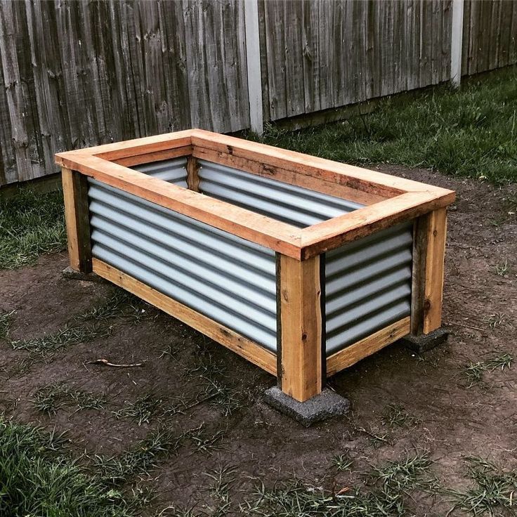 a wooden planter sitting on top of a dirt field