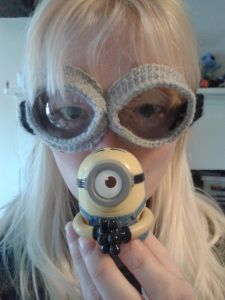 a woman holding a toy in front of her face with two large glasses on it