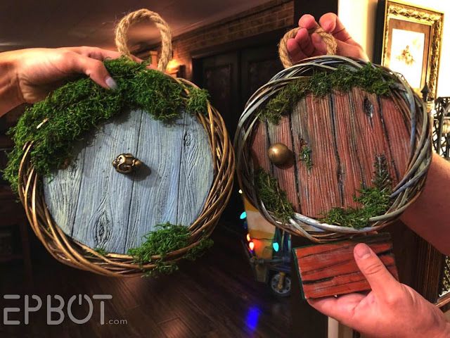 two people holding baskets with moss on them in front of a mirror and wall hangings