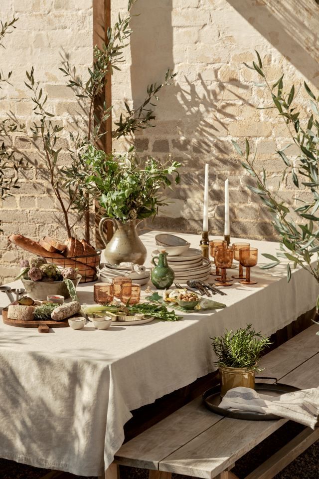 an outdoor table with olive trees and candles