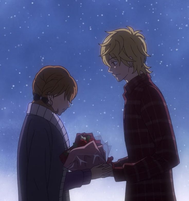 two people standing next to each other in front of snow covered sky with one person handing something