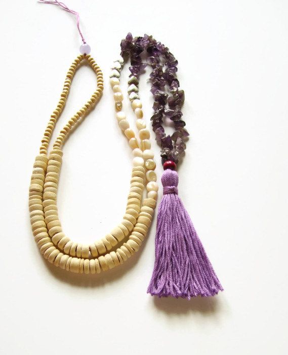 two necklaces with beads and tassels are on display, one is purple