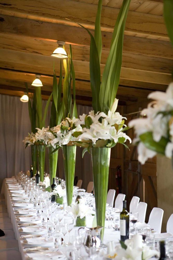 the long table is set with white flowers and place settings