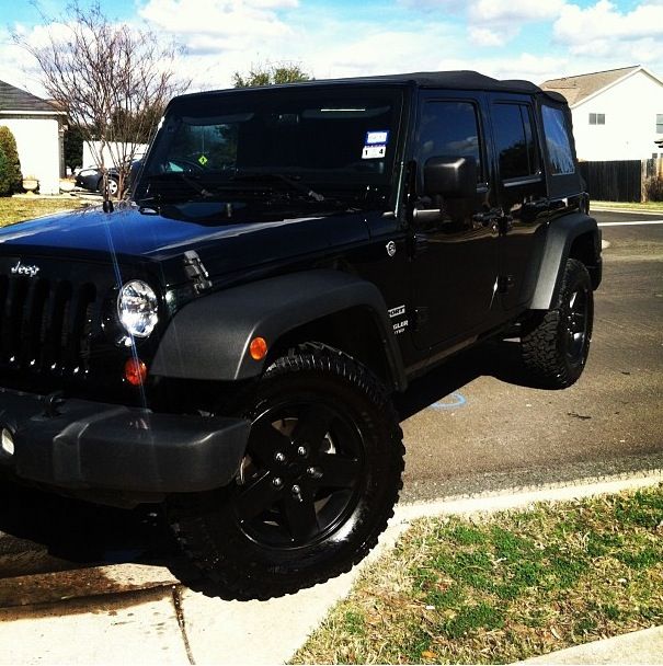 a black jeep is parked on the side of the road in front of a house