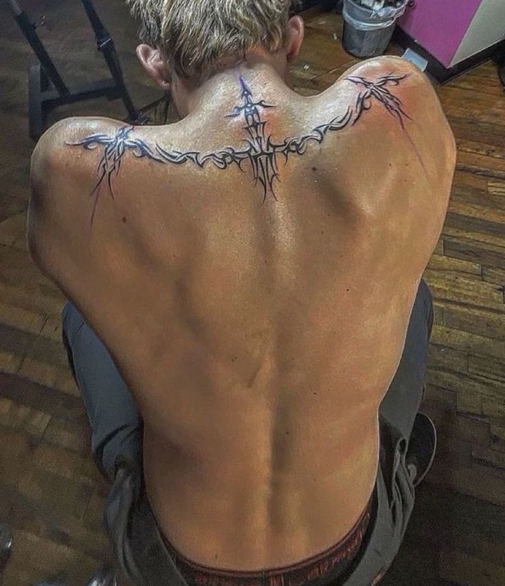 the back of a man with barbed wire tattoos on his upper and lower back shoulder