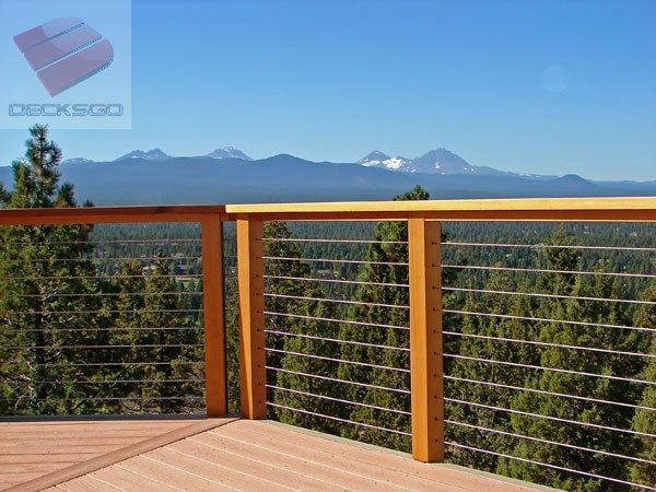 a wooden deck with metal railings and mountains in the background