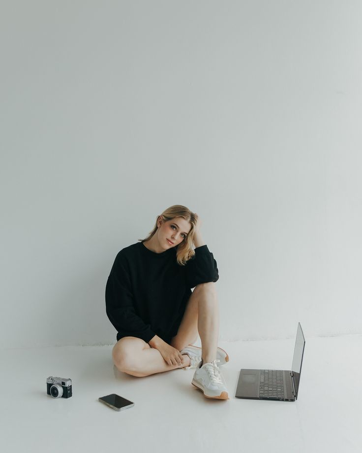 a woman sitting on the floor next to a laptop