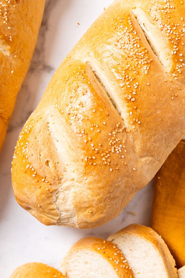 two loaves of bread sitting next to each other on a marble counter top with sesame seed sprinkles