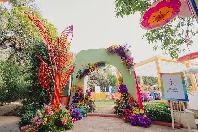 an archway decorated with colorful flowers and greenery in the middle of a park area