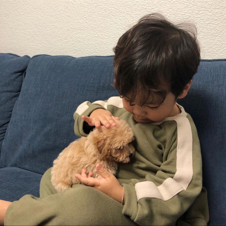 a little boy sitting on top of a blue couch holding a dog