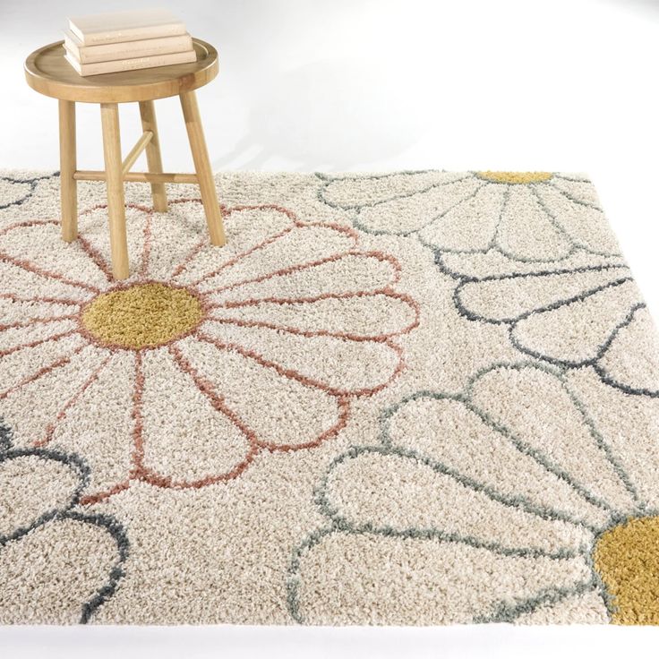 a table with two books on top of it next to a flower rug and stool