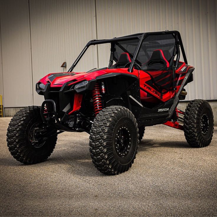 a red and black can - am rzr is parked in front of a building