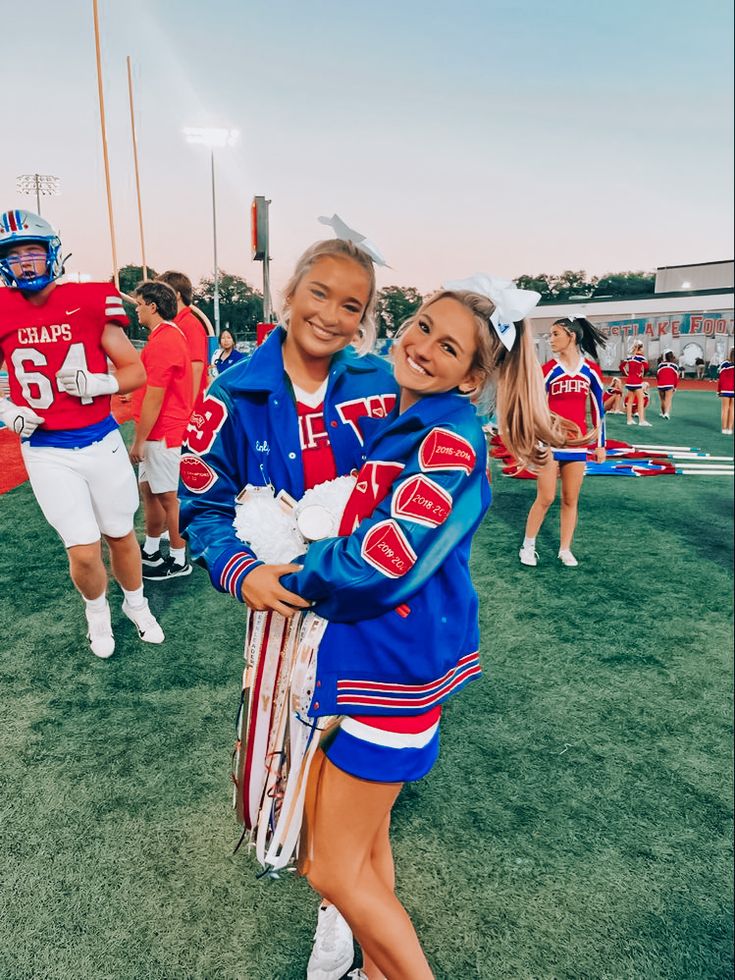 two cheerleaders pose for a photo on the field