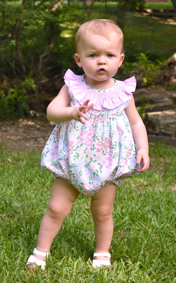 Meet Isla- Your little one's go-to floral dress for the warmer months. She's comfy, soft, and features the most gorgeous pink ruffled collar with smocking details. 100% Cotton, lined, with button back closure. * Matching Bubble Available. Flutter Sleeve Bubble Romper With Ruffles For Playtime, Spring Cute Bubble Romper With Ruffle Sleeves, Spring Bubble Romper With Ruffles And Flutter Sleeves, Spring Bubble Romper With Smock For Playtime, Spring Smock Bubble Romper For Playtime, Pink Smocked Dress For Playtime In Summer, Cute Bubble Romper For Spring Garden Party, Cute Bubble Romper For Garden Party In Spring, Pink Smocked Dress For Summer Playtime