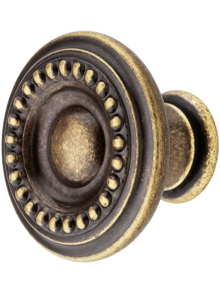 an antique brass door knob with rivets and beading on the outside, isolated against a white background