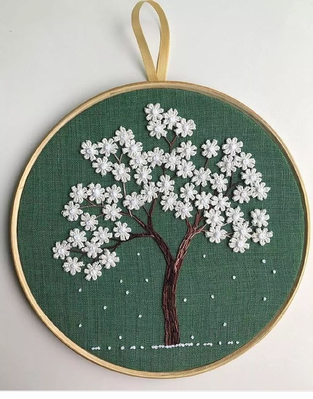 an embroidered tree with white flowers is hanging on a wooden hoop, and the words instagram are below it