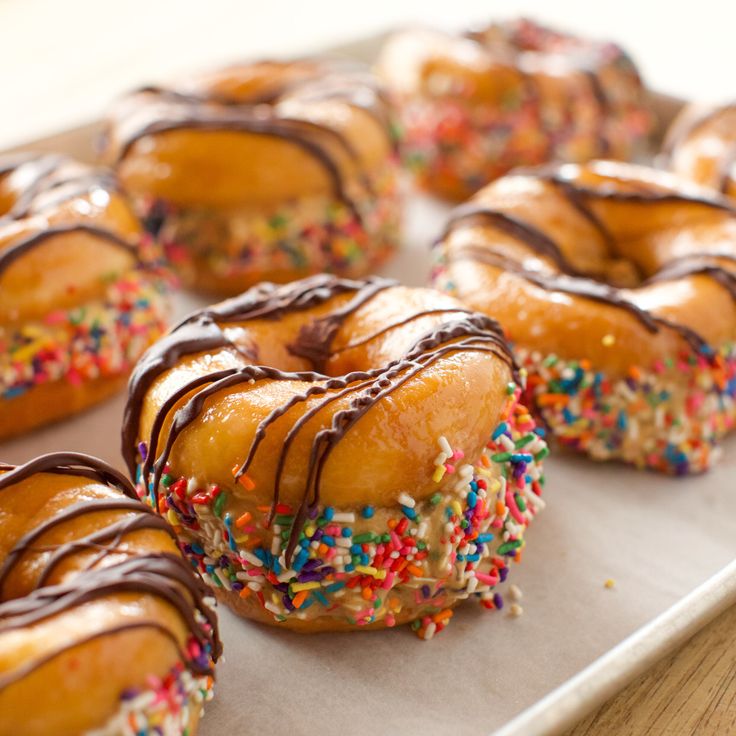 donuts with chocolate drizzle and sprinkles are on a tray