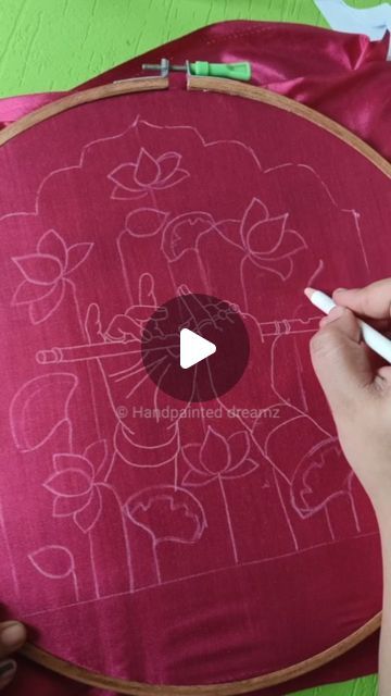 someone is working on an embroidery project with scissors and needleing threads in front of a red pillow