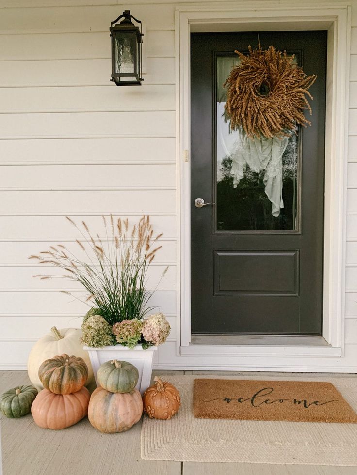 a front porch decorated for fall with pumpkins and gourds