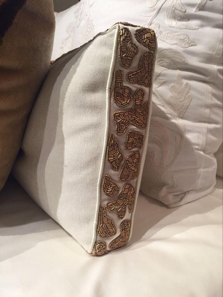 a white pillow sitting on top of a bed next to a brown pillow cover and pillows