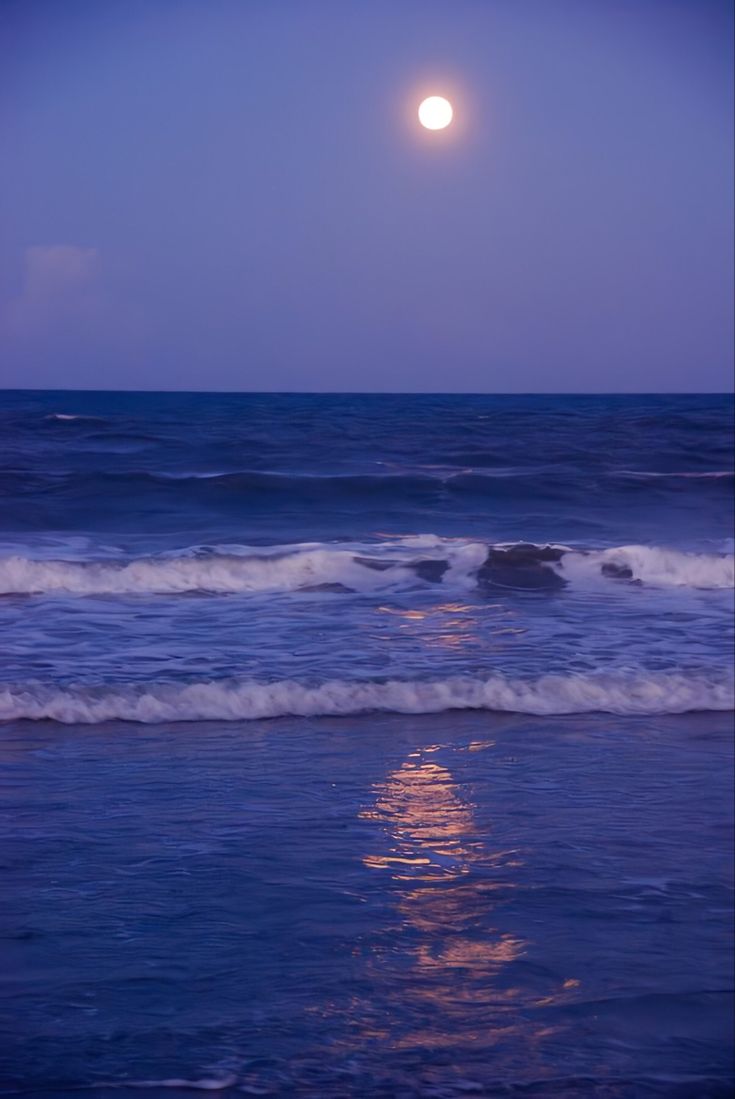 the moon shines brightly over the ocean as it reflects in the water's surface